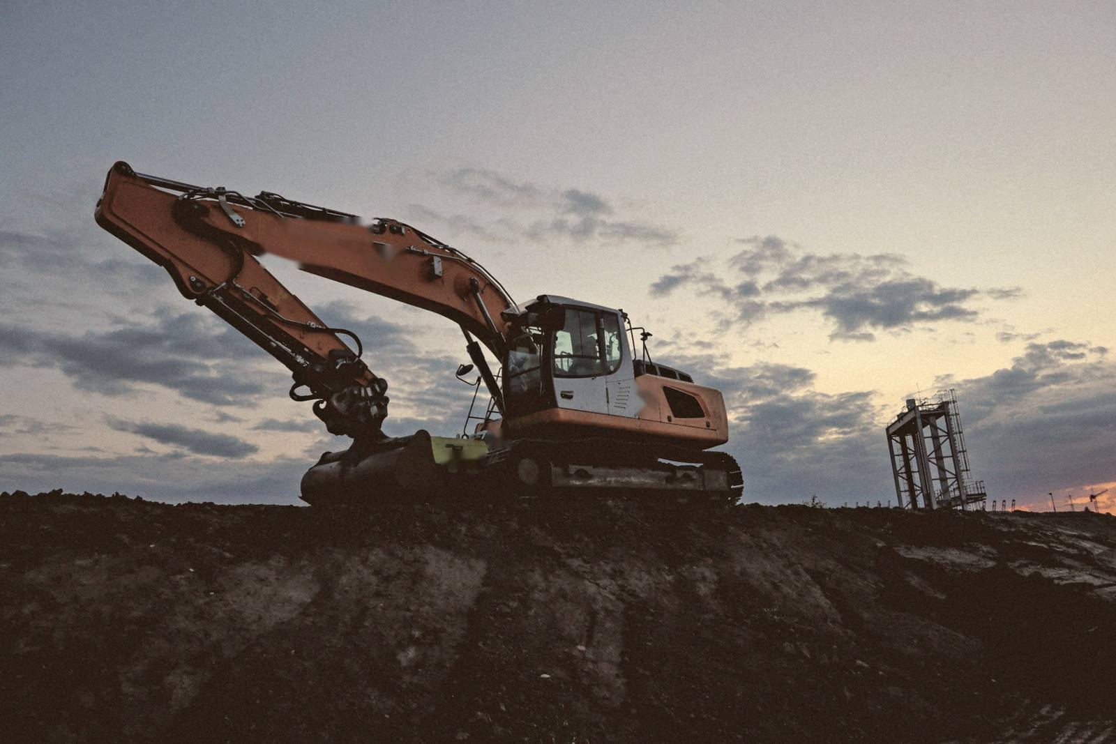 Excavadora de oruga sobre un terraplén al atardecer